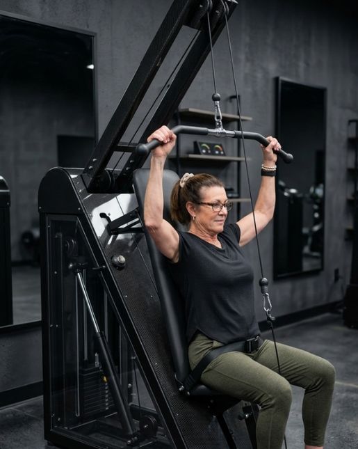 Woman performing overhead press using adaptive resistance machine